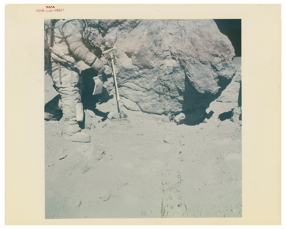 Astronaut Charles Duke stands at rock adjacent to House Rock